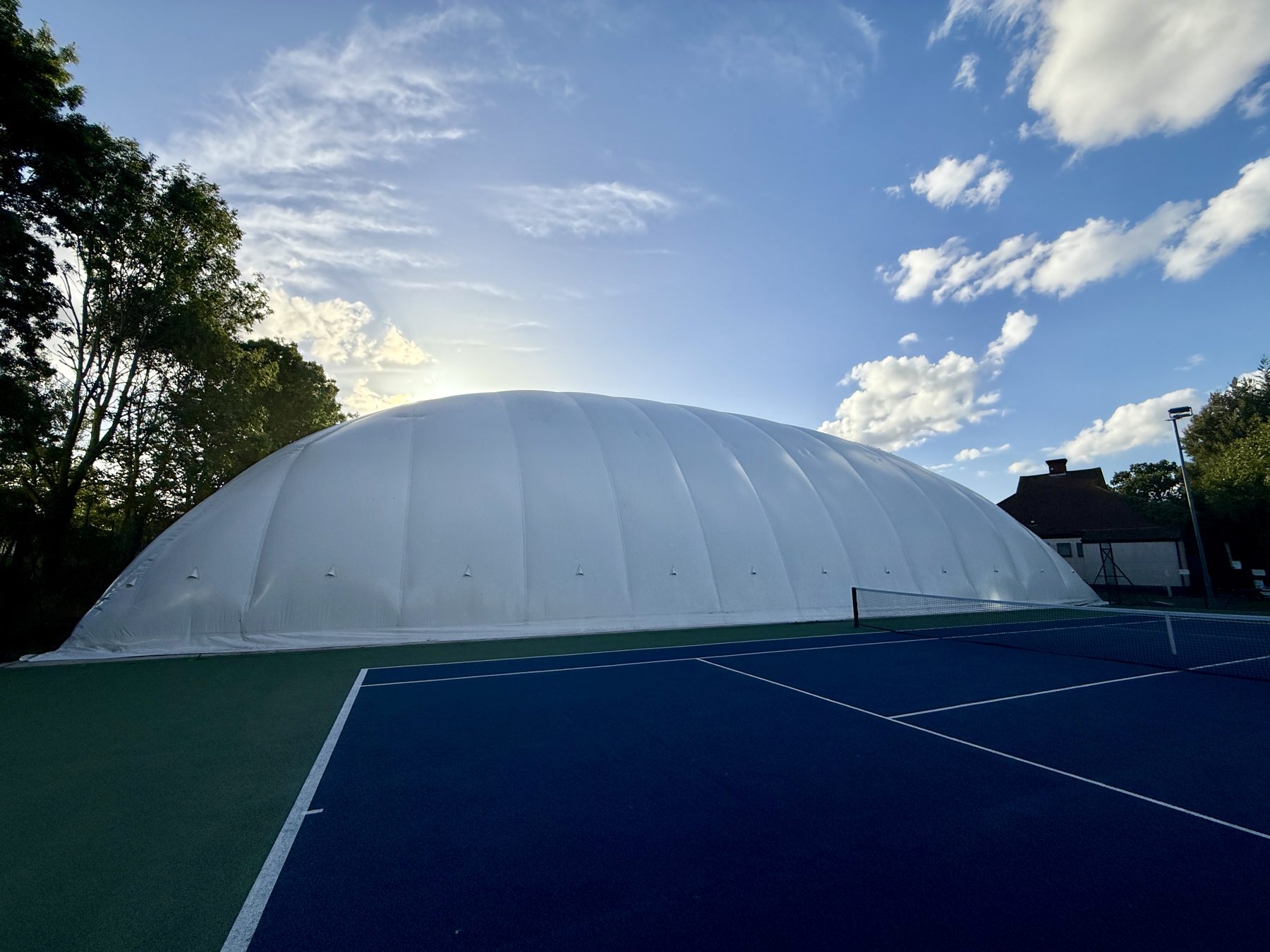 The permanent air dome at Chingford School of Tennis rising behind a resurfaced outdoor court