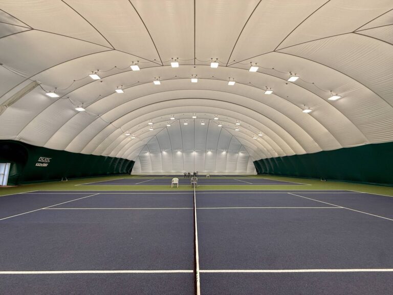 Inside the new DUOL permanent air dome at Chingford School of Tennis, looking the full length of the indoor courts under the lighting rig