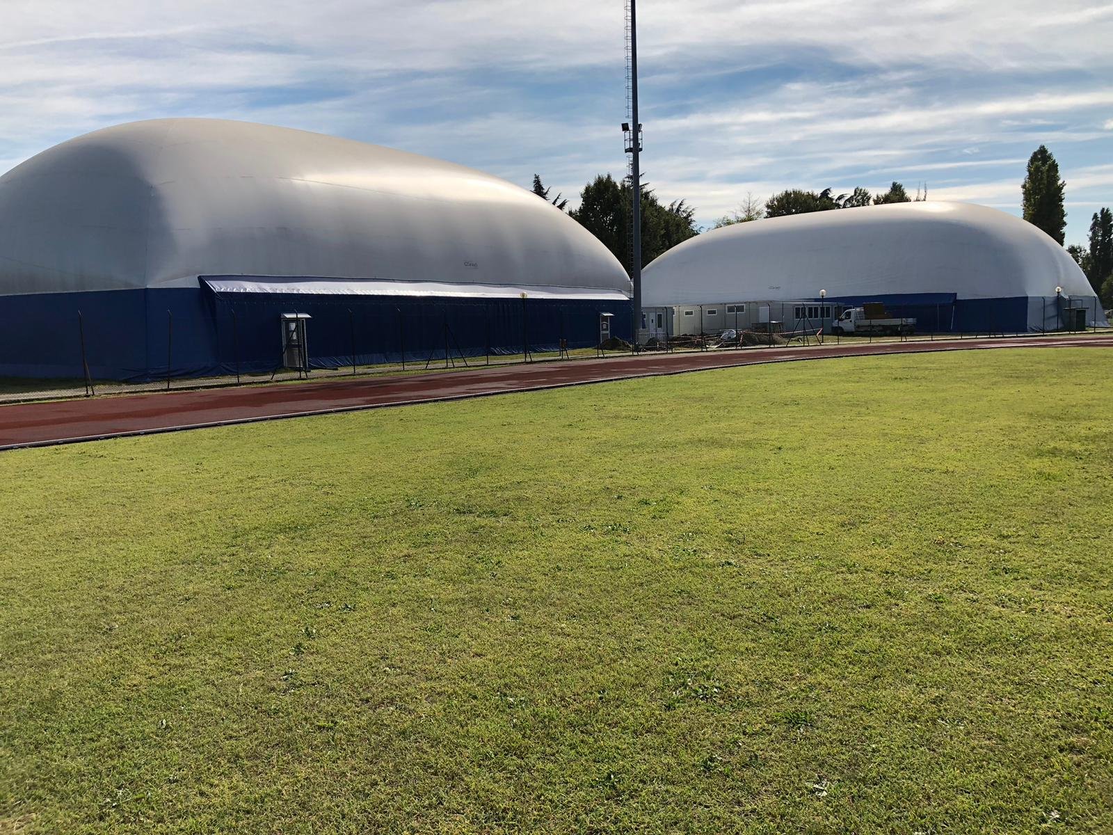 Two Covair geodesic halls beside a school sports field